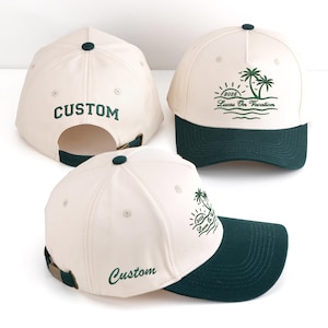Könnte beinhalten: Cremefarbene Baseballkappe mit dunkelgrünem Schirm und Knopf. Auf der Kappe ist das Wort "Custom" in Grün auf der Rückseite und vorne gestickt. Eine weitere Kappe hat ein Palmenmuster und den Text "2026 Lucas On Vacation" in Grün.