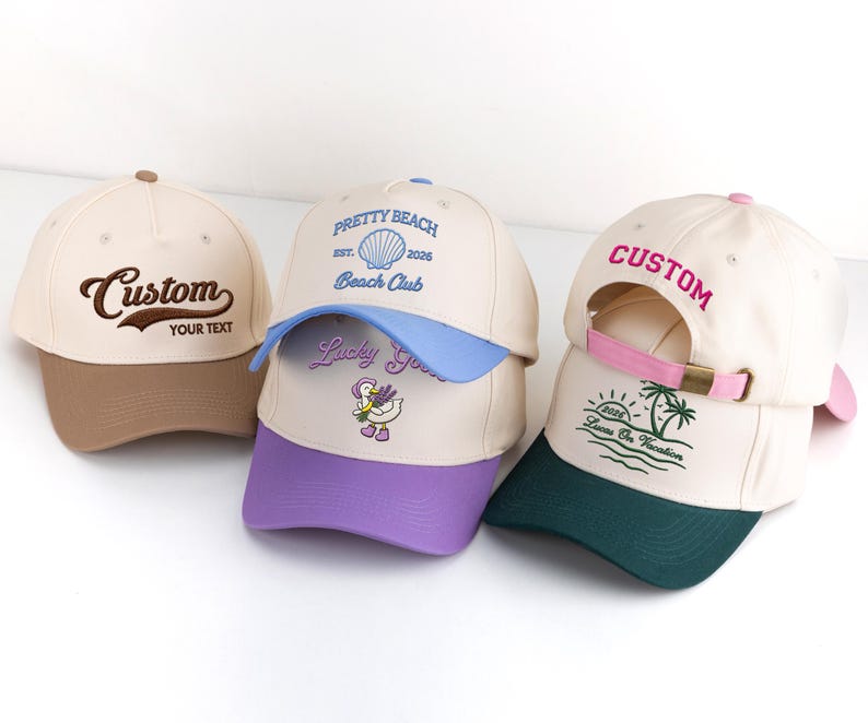 May include: Three baseball caps in cream, brown, blue, and purple. One cap has "Custom" and "YOUR TEXT" embroidered. Another says "PRETTY BEACH" and "Beach Club". The third has "CUSTOM" and "Loves On Vacation" embroidered.