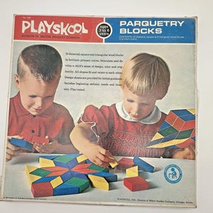 Könnte beinhalten: Vintage Playskool Parquetry Blocks Box mit zwei Kindern, die mit bunten Holzblöcken spielen. Die Box enthält Text über die Blöcke, die für Kinder im Alter von 3 bis 6 Jahren konzipiert sind. Die Blöcke sind rauten-, quadrat- und dreieckförmig.