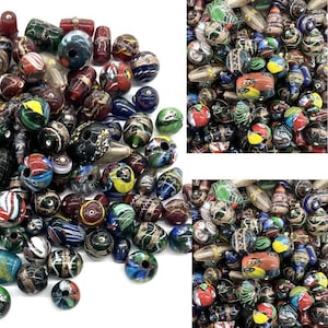 May include: A collection of colorful glass beads in various shapes and sizes. The beads feature a mix of colors including blue, red, green, and yellow, with intricate patterns and designs. Some beads have a striped or speckled appearance.
