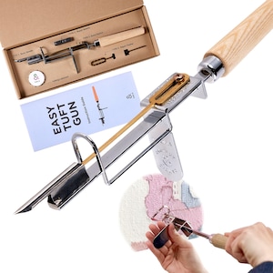 May include: A silver Easy Tuft Gun with a wooden handle and a set of repair tools in a cardboard box. The instruction guide is visible, with the text "Easy Tuft Gun". The tool is designed for rug making and tufting projects.