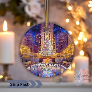Può includere: Un ornamento natalizio rotondo con una scena invernale di New York City, con un albero di Natale decorato e il testo "New York 2025". L'ornamento ha un cordino dorato per appenderlo.