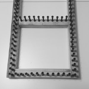 Puede incluir: Un telar de madera con clavijas de pl&aacute;stico negro. El telar es rectangular y tiene dos filas de clavijas.
