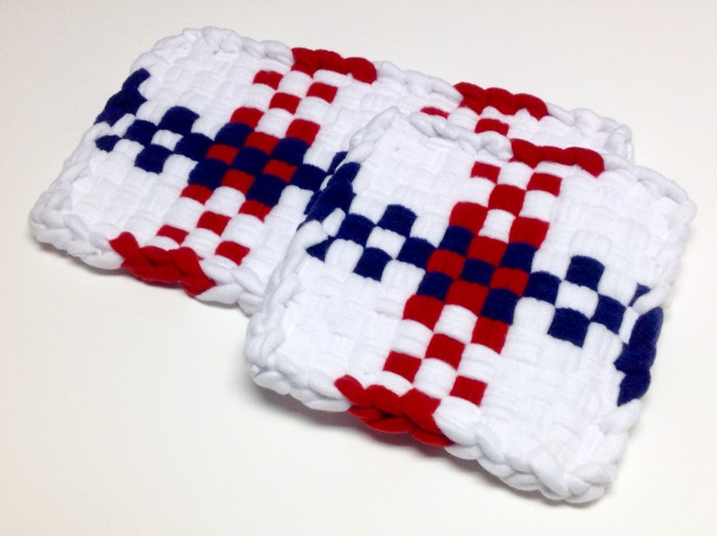 Puede incluir: Dos agarraderas de olla tejidas en un patr&oacute;n de cuadros rojos, blancos y azules. Las agarraderas est&aacute;n hechas de hilo blanco grueso con acentos rojos y azules.