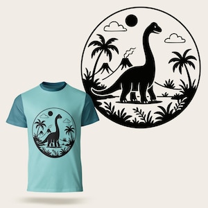 May include: A light blue t-shirt with a black dinosaur graphic inside a circular design. The graphic features a long-necked dinosaur, palm trees, a volcano, clouds, and a sun. The shirt has a crew neck and short sleeves.