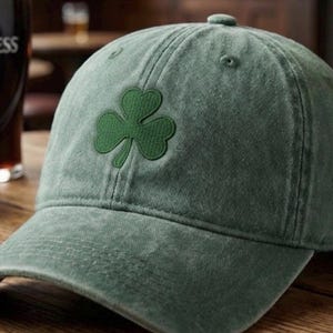 May include: Green baseball cap featuring a green shamrock emblem on the front. The cap has a curved brim and a button on top. The hat is made of a soft, textured fabric and is likely made of cotton.