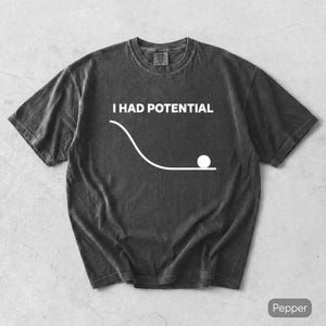 Könnte beinhalten: Ein anthrazitfarbenes Kurzarm-T-Shirt mit dem weißen Text I HAD POTENTIAL über einer Grafik, die eine geschwungene Linie zeigt, die in eine flache horizontale Linie übergeht, mit einem weißen Kreis am Ende des flachen Abschnitts auf der Vorderseite.