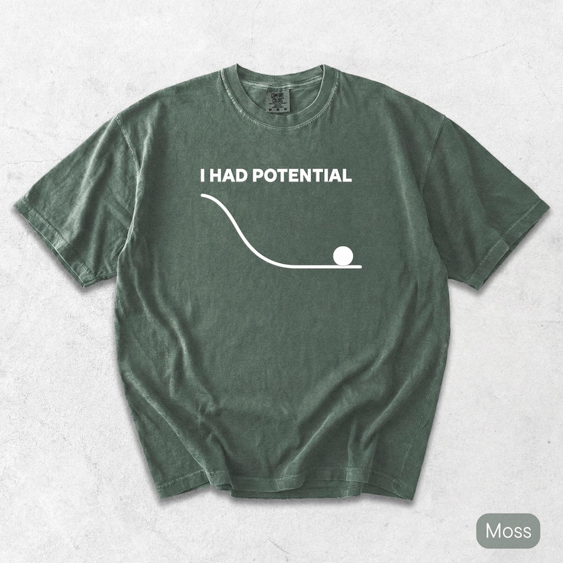 Pode incluir: Uma t-shirt de manga curta verde musgo com um gr&aacute;fico branco de uma curva descendente que termina numa linha plana com um c&iacute;rculo, acompanhada pelo texto branco "I HAD POTENTIAL" impresso numa fonte sem serifa na zona do peito.