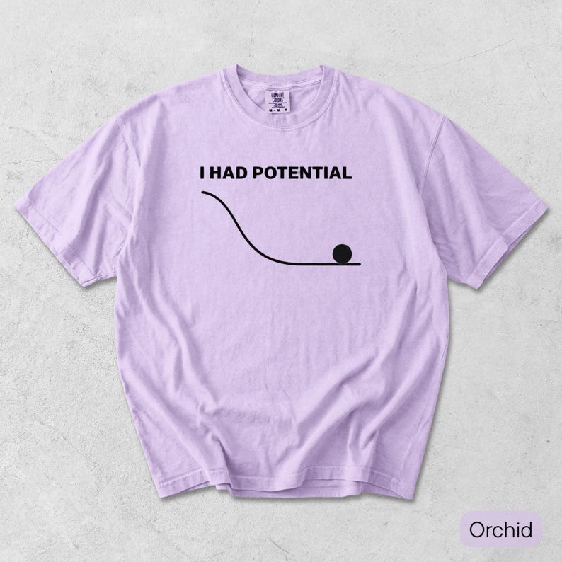 Pode incluir: Uma t-shirt de manga curta em violeta claro com o texto preto I HAD POTENTIAL sobre um gr&aacute;fico de uma linha curva e um c&iacute;rculo preto s&oacute;lido que representa uma bola no fundo de uma inclina&ccedil;&atilde;o. A t-shirt tem gola redonda e corte padr&atilde;o.