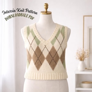 Peut inclure: Un gilet en tricot argyle crème avec un col en V. Le gilet présente un motif de losanges marron et verts. Le texte "Intarsia Knit Pattern DOWNLOADABLE PDF" est arqué au-dessus du gilet. Le gilet est présenté sur un mannequin.