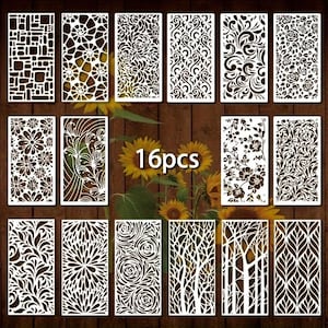 May include: Sixteen white decorative panels with diverse cut-out designs, including floral, geometric, and abstract patterns. The panels are arranged on a wooden surface with sunflowers in the background. The text "16pcs" is visible.