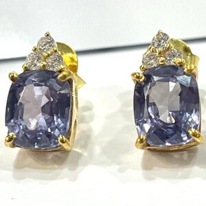 Può includere: Un paio di orecchini a bottone in oro. Ogni orecchino presenta una grande pietra preziosa viola chiaro a taglio cuscino, accentuata da un gruppo di piccole pietre preziose chiare nella parte superiore. Design classico ed elegante.