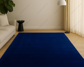 May include: A large, rectangular, solid navy blue rug. The rug is the focal point of a room with light-colored walls, a white sofa, and a black side table. A modern floor lamp with a white shade stands nearby. The rug is likely made of a soft material.