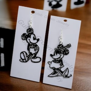 May include: Black Mickey Mouse and Minnie Mouse earrings displayed on white cards. The earrings are cut-out silhouettes with silver-coloured hooks. The cards have the text "Gulab Crown Jewelry".