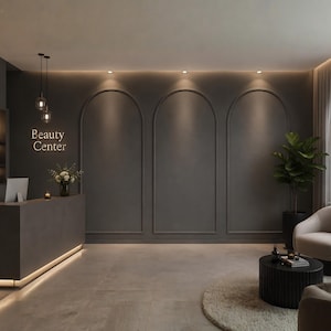 Op de afbeelding: Een ontvangstruimte met een donkergrijze muur met drie boogvormige panelen, een bijpassende receptiebalie met de tekst Beauty Center, twee hanglampen, een kamerplant, een ronde zwarte salontafel en een beige fauteuil.