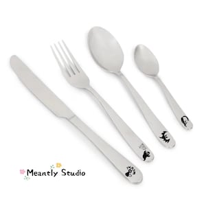 May include: A stainless steel flatware set featuring a knife, fork, and two spoons. Each handle is decorated with a black Halloween-themed design. The set includes a ghost, spiderweb, bat, and witch.