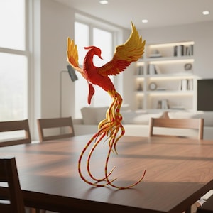 Op de afbeelding: Een gedetailleerde sculptuur van een feniksvogel, met rode, oranje en gele tinten. De vogel heeft uitgespreide vleugels en lange, vloeiende staartveren. Het staat op een houten tafel, wat suggereert dat het een decoratief item is.