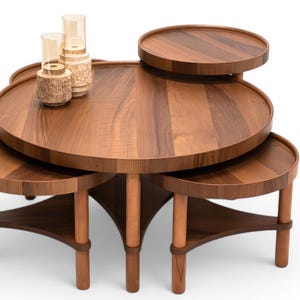 May include: A multi-tiered, wooden coffee table with a warm brown finish. The table features a large, round top with several smaller, circular platforms at varying heights. Decorative glass and textured vases sit on the top. The table's legs are cylindrical.