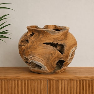 Op de afbeelding: Een ronde houten kom gemaakt van natuurlijke teakwortel, met een brede opening en een dikke, onregelmatige rand. De buitenkant toont een rijke bruine nerf met organische, uitgeholde texturen, diepe spleten en gladde oppervlakken.