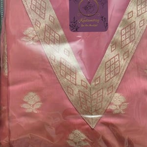 May include: A pink garment with a V-neck design, featuring gold floral patterns and a decorative gold border. The garment has a tag with the text "Kadambrii You Are Beautiful".