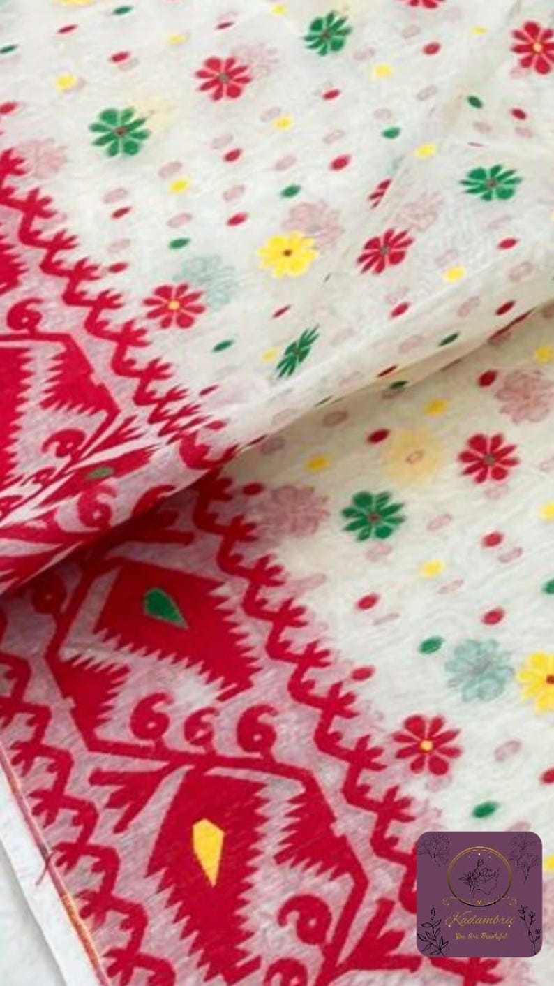 May include: White fabric with a red patterned border and scattered floral designs in red, green, and yellow. The fabric has a delicate, semi-transparent appearance, suggesting a lightweight material like cotton or silk. The design is likely for a scarf or shawl.