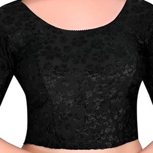 Pode incluir: Top de renda preta com decote redondo e mangas três quartos. O top tem um padrão floral e uma silhueta ajustada, adequado para sobreposição ou uso individual.