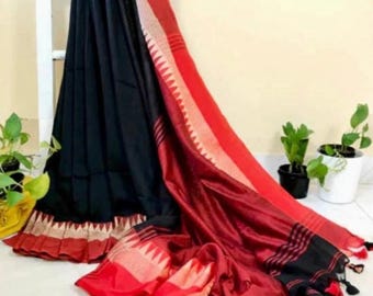 May include: A black and red saree with intricate border detailing. The saree features a contrasting red border with a geometric pattern and tassels. The fabric drapes elegantly, showcasing the rich colors and textures.