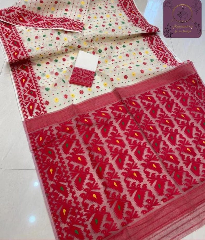 May include: A cream-colored textile with a red and white patterned design. The fabric features a repeating geometric pattern in red, with accents of yellow and green. A smaller, matching piece is also visible.