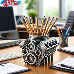 May include: A silver engine block pencil pot filled with pencils. The pencil pot is designed to resemble an engine, with detailed gears and cylinders. The pencils are wooden with pink erasers. The words "FREE SHIPPING" are in the top left corner.