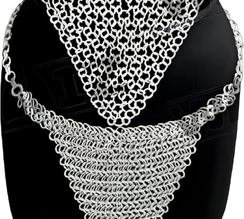 May include: A silver chainmail garment, likely a neck piece, displayed against a black background. The chainmail is made of small, interlocking metal rings, creating a flexible, textured surface. The design includes a triangular section and a longer, draped section.