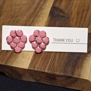 Könnte beinhalten: Rosa Ohrstecker in Form von Trauben. Die Ohrringe werden auf einer weißen Karte mit dem Text "THANK YOU" und einem Smiley präsentiert. Der Hintergrund ist eine Holzoberfläche.