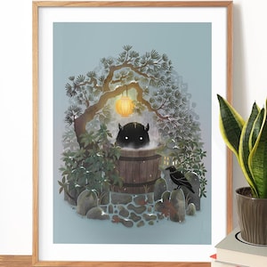 May include: A framed art print depicts a whimsical scene of a creature relaxing in a wooden hot tub. The artwork features a lantern, a crow, and lush greenery, creating a serene and imaginative atmosphere. The print is framed in a light-colored wooden frame.