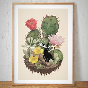 May include: Watercolor print of a black deer with white antlers amidst cacti, yellow and pink flowers, and succulents. The artwork is set on a small island with a light beige background, framed in a wooden frame.