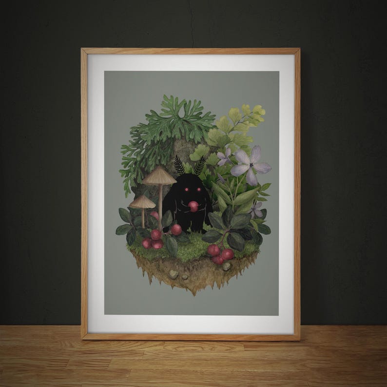 May include: A framed art print featuring a dark, silhouetted creature with glowing red eyes holding a red berry, surrounded by green foliage, ferns, light purple flowers, mushrooms, and red berries on a floating patch of earth with a gray background.