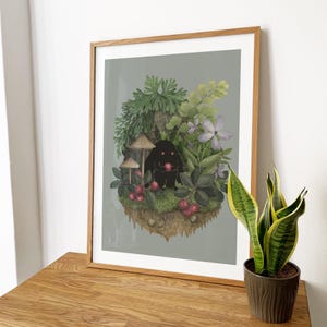 May include: A framed art print featuring a dark, fuzzy creature with glowing pink eyes holding a red berry, surrounded by green foliage, mushrooms, and purple flowers on a floating patch of earth against a solid light gray background.