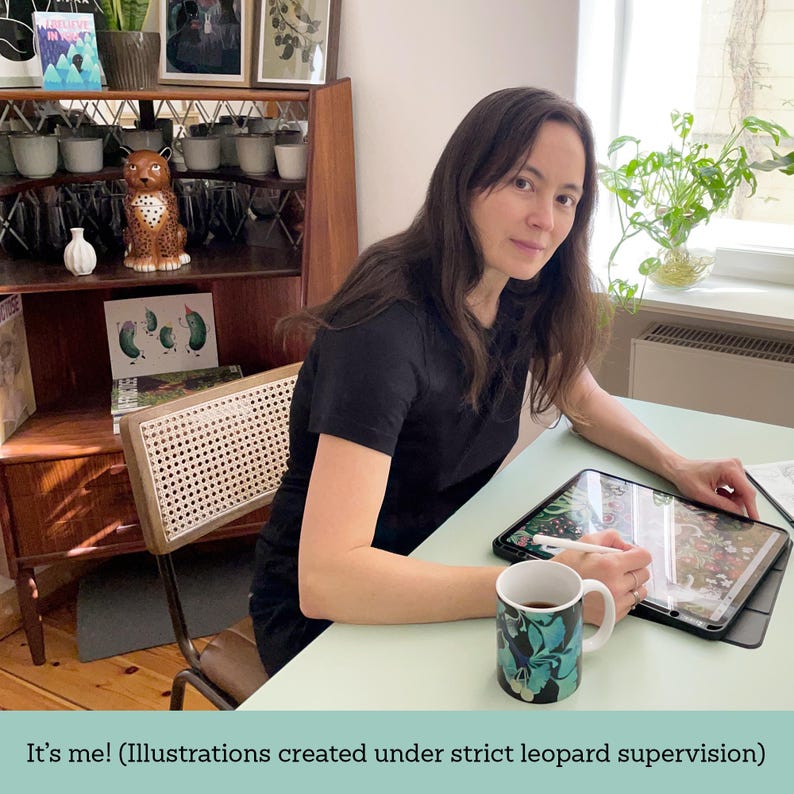May include: A person seated at a mint green table, working on a tablet with a stylus. A mug with a floral design sits on the table. A ceramic leopard figurine and artwork are visible in the background. The text at the bottom reads "It's me! (Illustrations created under strict leopard supervision)".