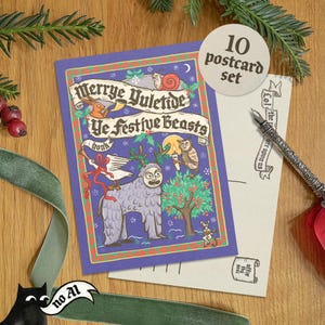 May include: A set of 10 postcards with a whimsical illustration. The main postcard features the text "Merrye Yuletide Ye Festive Beasts" with various fantastical creatures. A pen and a sprig of pine are also visible.