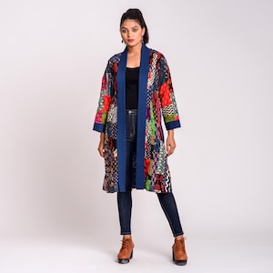 Könnte beinhalten: Eine langärmelige, knielange Jacke mit offener Vorderseite, die ein lebhaftes Patchwork-Design mit verschiedenen geometrischen und floralen Mustern in Rot-, Blau-, Grün- und Gelbtönen aufweist, abgerundet durch einen einfarbigen dunkelblauen Saum.