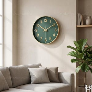 Könnte beinhalten: Eine runde Wanduhr mit dunkelgrünem Zifferblatt und goldfarbenen Zeigern und Ziffern. Die Uhr hat einen goldfarbenen Rahmen und ist an einer hellen Wand befestigt. Die Uhr hat einen Durchmesser von etwa 30 cm.
