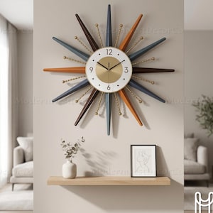 Peut inclure: Une horloge murale de style rétro avec un cadran et des aiguilles dorées. L'horloge a un cadran blanc avec des chiffres noirs et des accents dorés. Les bras en forme d'éclat d'étoile sont dans des tons de bleu, marron et orange. Une pièce décorative.