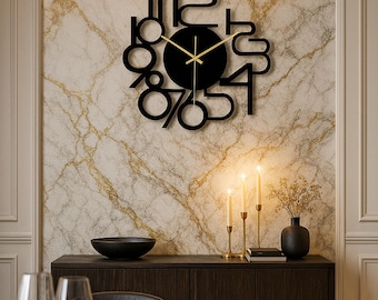 Op de afbeelding: Een moderne zwarte wandklok met een ronde wijzerplaat en gouden wijzers. De cijfers zijn gestileerd en uitgesneden, wat een uniek ontwerp creëert. De klok is bevestigd aan een marmerpatroon muur, wat een vleugje elegantie toevoegt.
