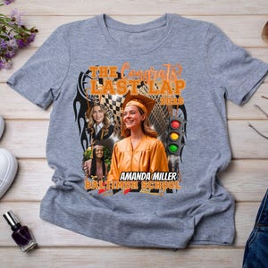 May include: A heather gray short-sleeve t-shirt featuring a graphic print with the text THE CONGRATS LAST LAP 2025, AMANDA MILLER BALTIMORE SCHOOL, a traffic light, a checkered flag, and three photos of a graduate in a cap and gown.