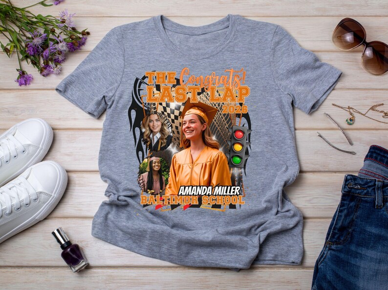 May include: A heather gray short-sleeve t-shirt featuring a graphic print with the text THE CONGRATS LAST LAP 2025, AMANDA MILLER BALTIMORE SCHOOL, a traffic light, a checkered flag, and three photos of a graduate in a cap and gown.