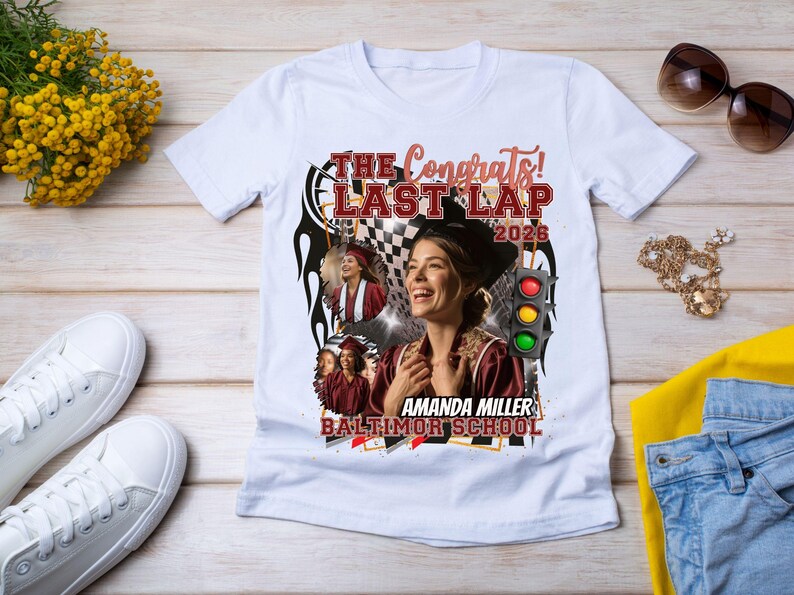 May include: White t-shirt with a graphic design featuring a woman, the text "The Congrats! Last Lap 2026", and the name "Amanda Miller, Baltimor School". The design includes a checkered flag and a traffic light.