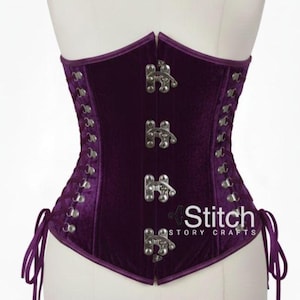 Puede incluir: Un corsé de terciopelo morado oscuro con cierres y ojales plateados. El corsé tiene un diseño estructurado con la espalda con cordones y se muestra en un maniquí. El texto "Stitch Story Crafts" es visible.