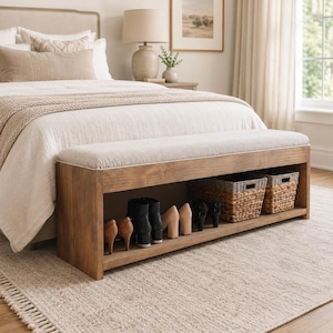Peut inclure: Un banc de rangement rectangulaire en bois avec un coussin d'assise rembourré beige clair. La base comporte une étagère ouverte contenant deux paniers en jonc de mer tressé et plusieurs paires de chaussures, dont des talons, des bottines et des escarpins.