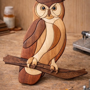 May include: A wooden owl sculpture perched on a branch. The owl is crafted from various shades of brown wood, with detailed feather patterns and large, expressive eyes. The sculpture is set against a natural wood background.