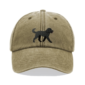 Könnte beinhalten: Khaki Baseball Cap mit einer schwarzen Hundeillustration. Die Kappe hat einen gebogenen Schirm und einen verstellbaren Riemen. Die Hundeillustration befindet sich auf der Vorderseite. Die Kappe besteht aus einem weichen, abgenutzten Material.
