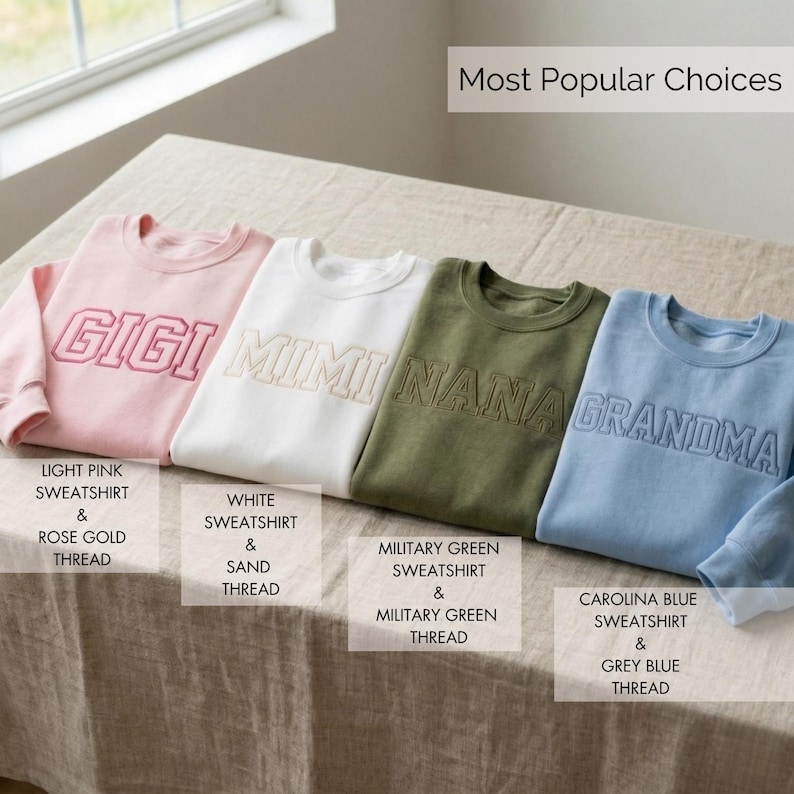 Op de afbeelding: Vier crewneck sweatshirts in lichtroze, wit, legergroen en lichtblauw. Elk sweatshirt heeft een geborduurde naam: GIGI, MIMI, NANA en GRANDMA. Het roze sweatshirt heeft ros&eacute;goud draad, het witte heeft zanddraad, het groene heeft groen draad en het blauwe heeft grijsblauw draad.