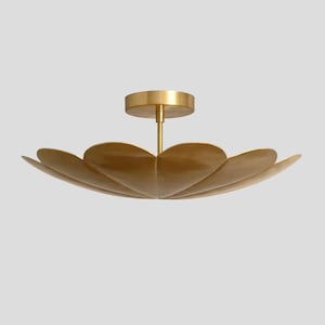 Op de afbeelding: Een goudkleurige plafondlamp met een bloemachtig ontwerp. De armatuur heeft een centrale steel en een cirkelvormige basis, met bloembladachtige elementen die naar buiten uitsteken. Het licht is gemaakt van metaal en heeft een warme, metallic afwerking.